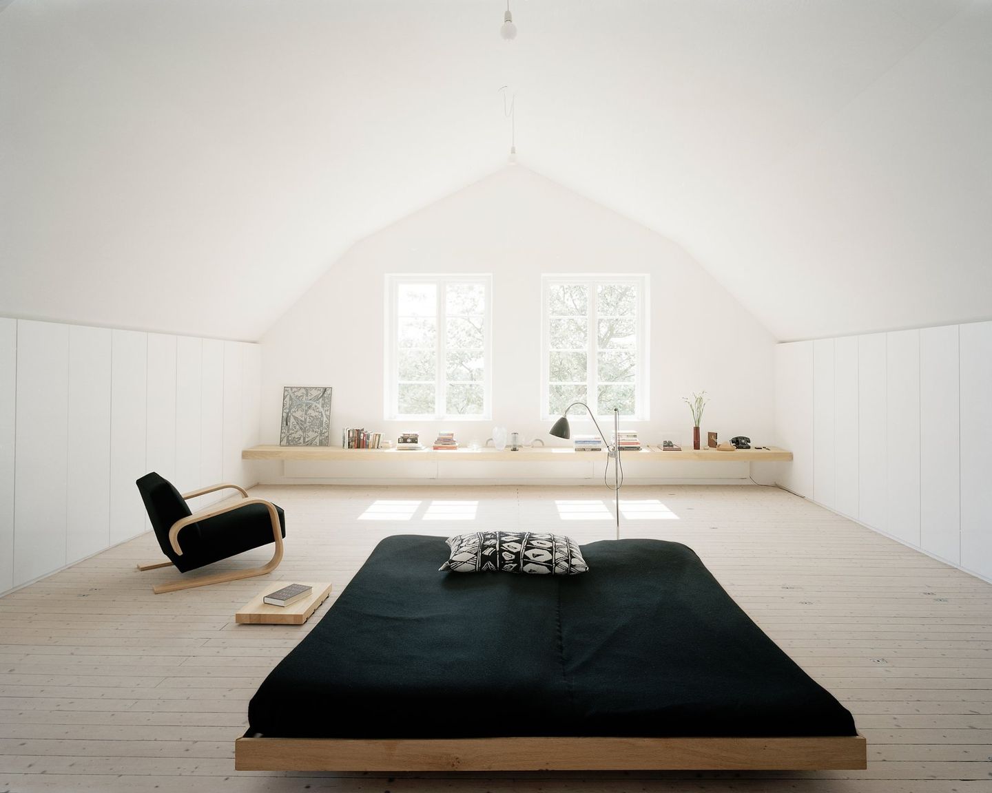 Jadikan tempat tidur rendah sebagai titik pusat desain untuk ruangan dengan negative space dominan.
